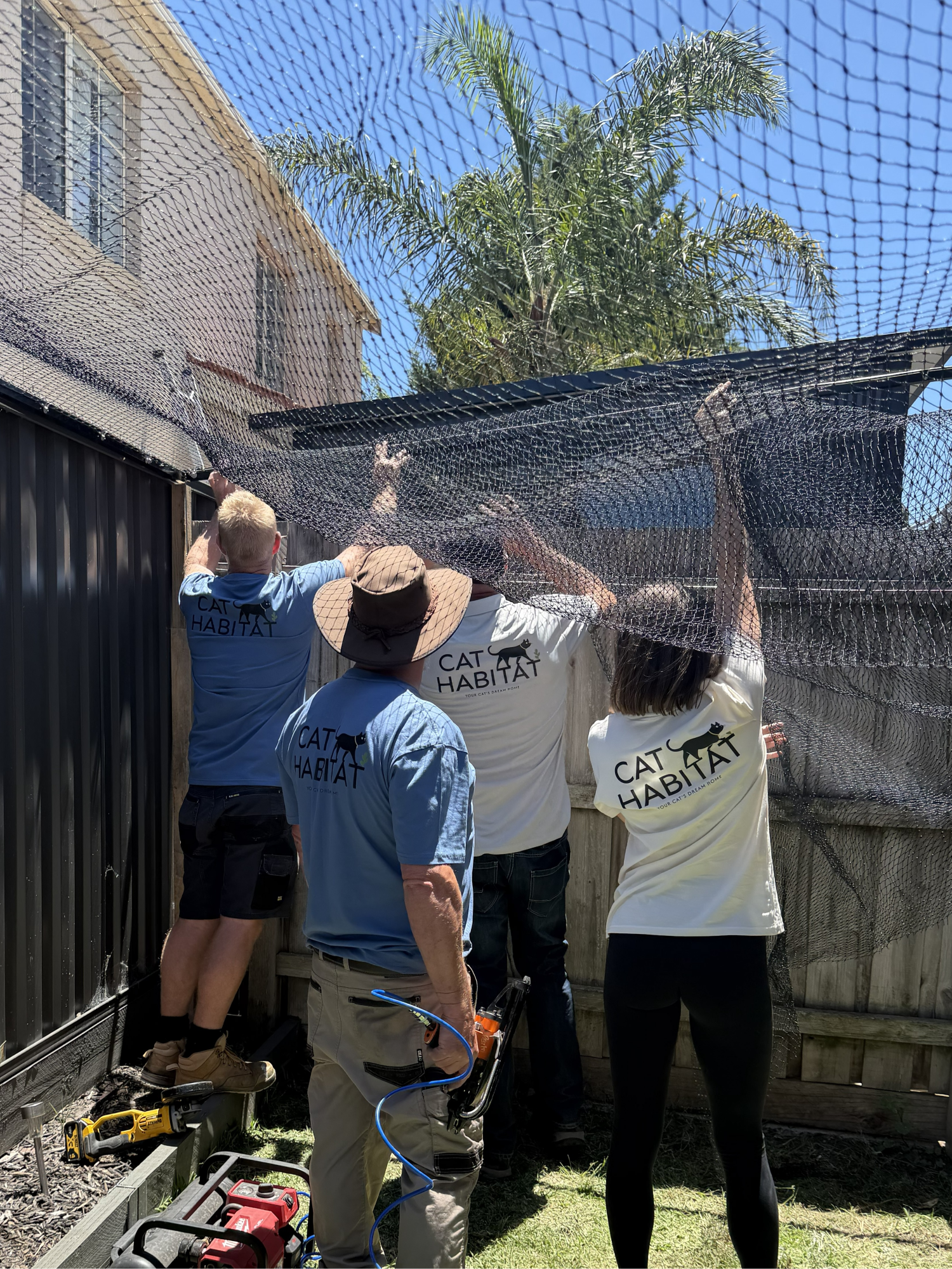 Four people building a full yard cat enclosure